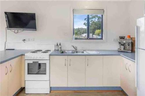 uma cozinha com um fogão, um lavatório e uma janela em Beach Cottage - Port Arthur em Port Arthur