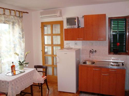 eine Küche mit einem weißen Kühlschrank und einem Tisch mit Stühlen in der Unterkunft Apartments with a parking space Sukosan, Zadar - 14742 in Sukošan