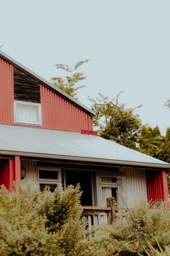 a red and white house with trees in the background at Waitomo Village Chalets home of Kiwipaka in Waitomo Caves