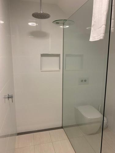 uma casa de banho com uma cabina de duche em vidro e um WC. em Rainbow Beach Dream Studio Motel Style Apartment em Rainbow Beach