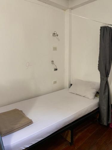 a bed in a room with a white wall at Dream Home Hostel in Vientiane