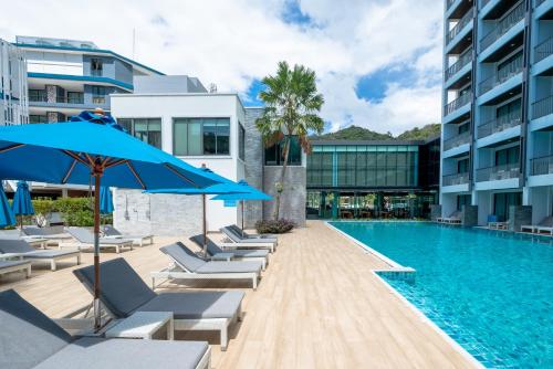 a swimming pool with lounge chairs and blue umbrellas at BlueSotel Krabi AoNang Beach- SHA Extra Plus in Ao Nang Beach