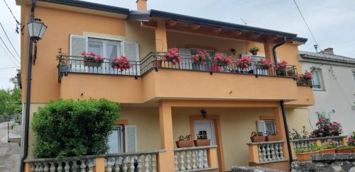 a yellow house with flowers on the balconies at Apartments with a parking space Smrika, Kraljevica - 14812 in Šmrika