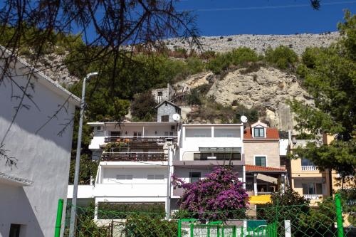 a white apartment building with a hill in the background at Apartments by the sea Krilo Jesenice, Omis - 14823 in Krilo