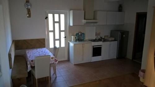 eine Küche mit weißen Schränken, einem Tisch, einem Tisch und Stühlen in der Unterkunft Apartments with a parking space Orebic, Peljesac - 14857 in Orebić