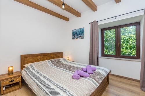 a bedroom with a bed with purple slippers on it at Holiday house with a parking space Risika, Krk - 14860 in Vrbnik
