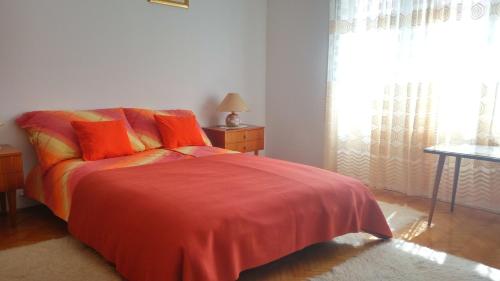 - une chambre avec un lit doté d'oreillers orange et une fenêtre dans l'établissement Apartments with a parking space Zagreb - 14890, à Zagreb