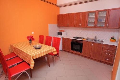 una cucina con tavolo con sedie rosse e tavolo con vaso di Apartments by the sea Trogir - 14907 a Trogir