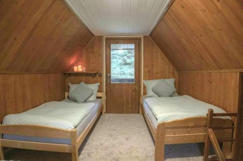 two beds in a room with wooden walls at Charming cottage KLARA with Sauna, Nature&Privacy near Prague in Malé Kyšice