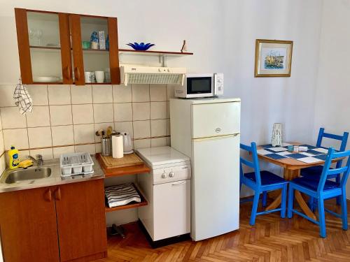 eine kleine Küche mit einem weißen Kühlschrank und einem Tisch in der Unterkunft Apartments and rooms by the sea Opatija - 14937 in Opatija