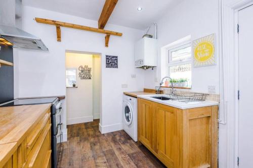 a kitchen with a sink and a washing machine at Charming 3 Bed Home in the Garden Quarter, Chester in Chester