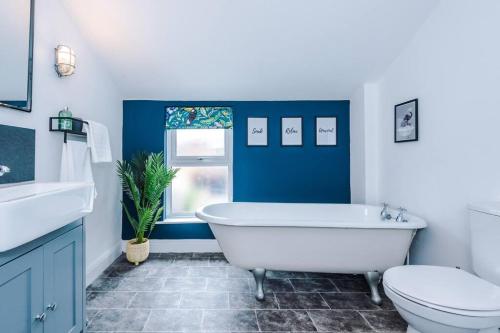 a blue and white bathroom with a tub and a toilet at Charming 3 Bed Home in the Garden Quarter, Chester in Chester