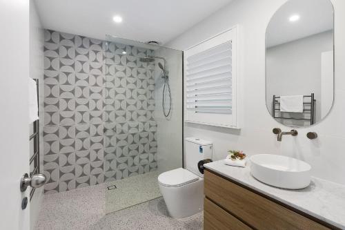 a bathroom with a toilet and a sink and a mirror at Terrace Lofts Apartments in Ocean Grove
