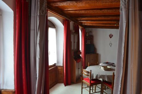 een kamer met rode gordijnen, een tafel en een raam bij Studio Au Millésime in Riquewihr