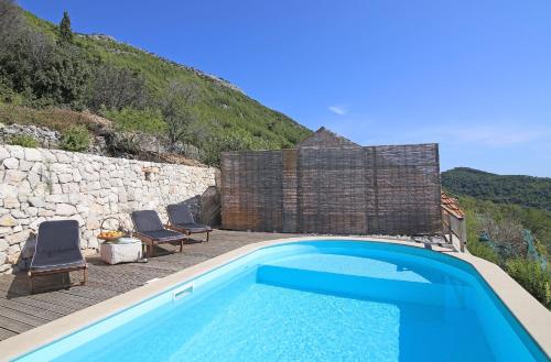 a swimming pool with two chairs next to a stone wall at Family friendly house with a swimming pool Babino Polje, Mljet - 14926 in Babino Polje