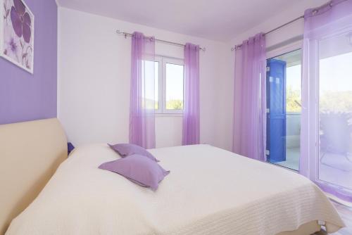 una camera da letto con un letto bianco con tende viola di Apartments by the sea Cove Pribinja, Hvar - 15083 a Hvar