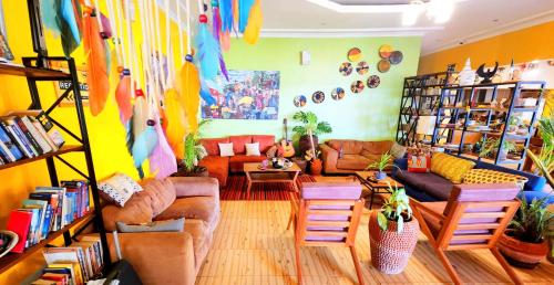 Yambi Guesthouse في كيغالي: غرفة معيشة بها كنب وكراسي وكتب