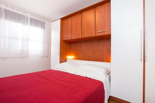a bedroom with a red bed and wooden cabinets at Apartments with a parking space Punat, Krk - 15094 in Punat