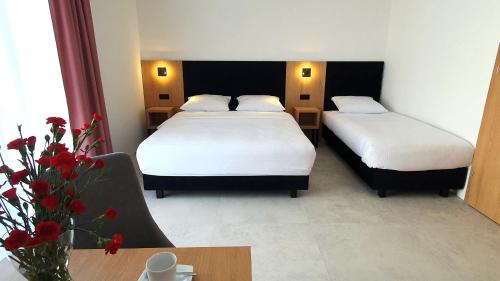 a hotel room with two beds and a table with flowers at Bursztynowa Rosa & Wypożyczalnia rowerów elektrycznych in Łeba