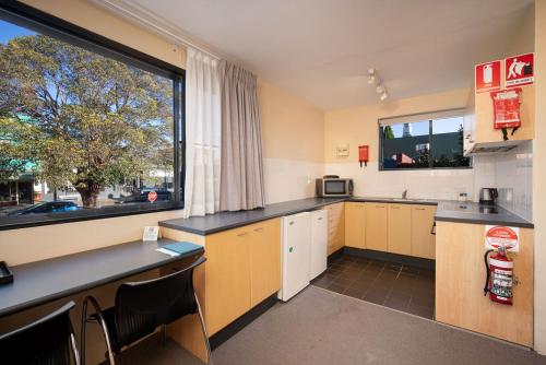 a kitchen with yellow cabinets and a large window at Drummoyne Furnished Apartments in Sydney