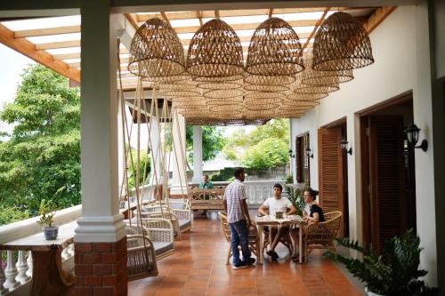 un grupo de personas sentadas en mesas en un porche en Casa Nemo Beach Resort & Spa en Sabong