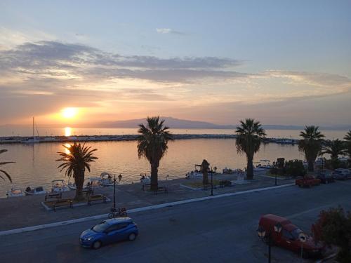 a sunset over a body of water with palm trees and cars at ANGELS HOUSE in Skala Kallirakhis