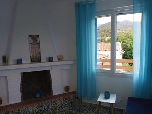a living room with a fireplace and a window at ANGELS HOUSE in Skala Kallirakhis