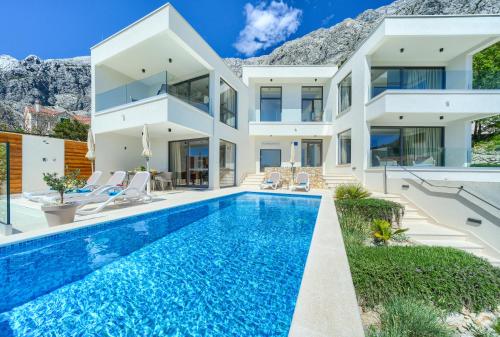 eine Villa mit einem Pool und einem Haus in der Unterkunft Villa Bellevue Bast in Baška Voda