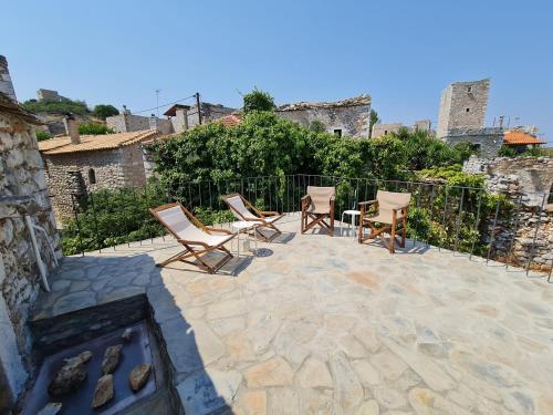 a group of chairs sitting on a patio with a fireplace at Traditional Stone House in Láyia