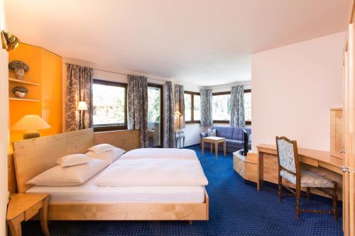 a hotel room with two beds and a desk at Rosa Canina Superior in Sankt Anton am Arlberg