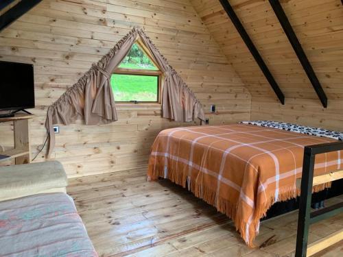 Dormitorio en cabaña de madera con cama y ventana en Mirador Valeisa, en Guatavita