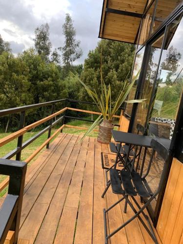 a wooden deck with two chairs and a plant on it at Mirador Valeisa in Guatavita