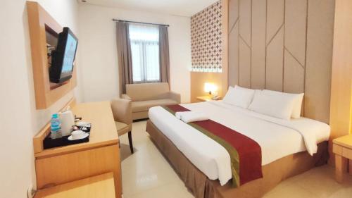 a hotel room with a large bed and a chair at Al Azhar Azhima Hotel Resort and Convention in Solo