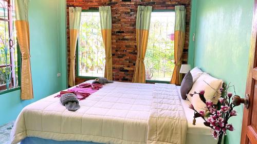a bedroom with a large bed in a room with windows at Swiss Chalet Garden, Pool Resort in Krabi town