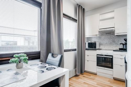 kuchnia z białymi szafkami i stołem z niebieskim krzesłem w obiekcie Majoituspalvelu Nurmi Oy City Apartment Kauppakatu 52 w mieście Raahe