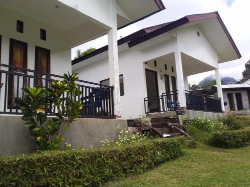 een wit huis met een veranda en een tuin bij SHILA GUEST HOUSE in Kelimutu