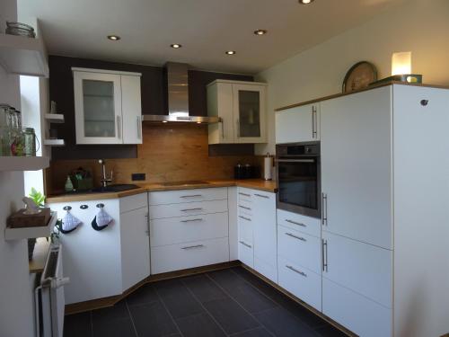 a kitchen with white cabinets and a black floor at Hygge Hus Langstedt in Langstedt