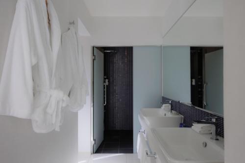 a white bathroom with three sinks and a mirror at Homm Stay Yumiha Okinawa by Banyan Tree Group in Onna