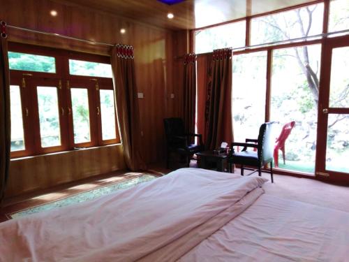 a bedroom with a large bed and large windows at Chogho-Sar Huts in Ponedas