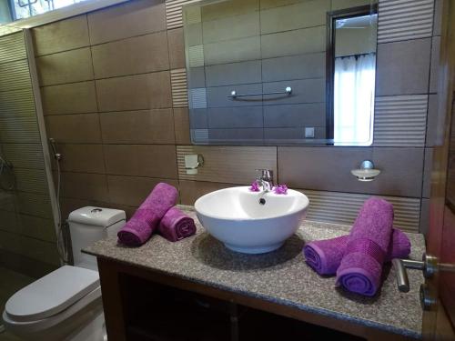 a bathroom with a sink and purple towels on a counter at Beach Villa in Nosy Be