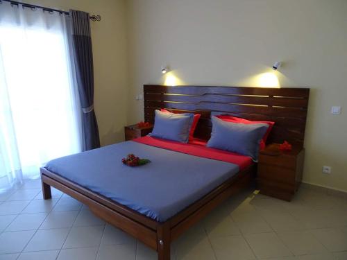 a bedroom with a large bed with blue and red pillows at Beach Villa in Nosy Be