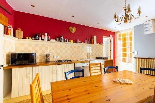 a kitchen with a wooden table and a red wall at Le Gite du Chevreuil, 200 Mètres de BEAUVAL in Saint-Aignan