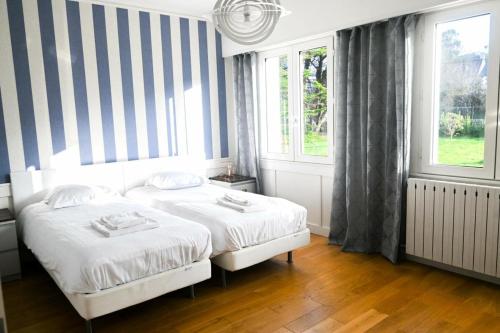 a bedroom with two beds and two windows at Résidence Le Lenn-louannec - Maisons & Villas pour 6 Personnes 784 in Lannion
