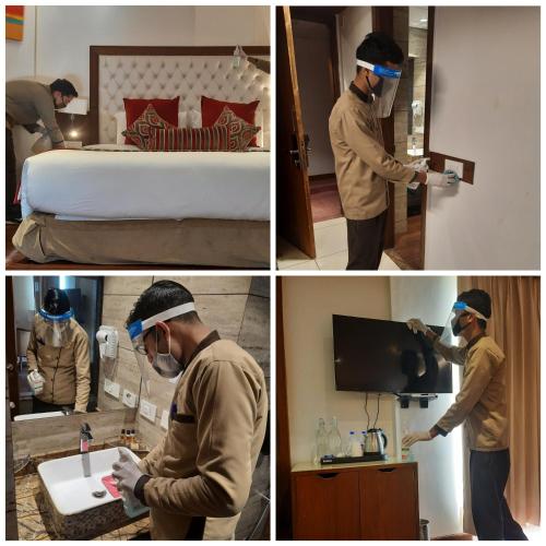 a man cleaning a bedroom with a mask on his face at Royale Retreat Hotel & Spa Near Mall Road in Shimla