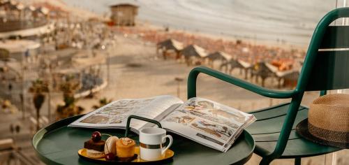 een groene tafel met een boek en een kopje en een krant bij Crowne Plaza Tel Aviv Beach, an IHG Hotel in Tel Aviv