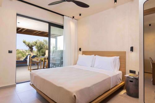 a bedroom with a large bed and a balcony at Pnoes Luxury Suites in Paliouri