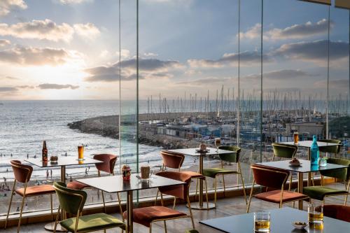 een restaurant met tafels en stoelen en uitzicht op de oceaan bij Crowne Plaza Tel Aviv Beach, an IHG Hotel in Tel Aviv