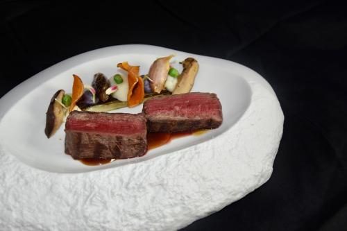 a white plate with two pieces of meat and vegetables at D-Resort Šibenik in Šibenik