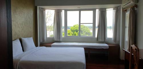 a bedroom with two beds and a large window at บ้านรับพร in Nakhon Phanom