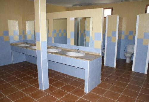 a public bathroom with three sinks and a toilet at Kampaoh Cabañeros in Navas de Estena